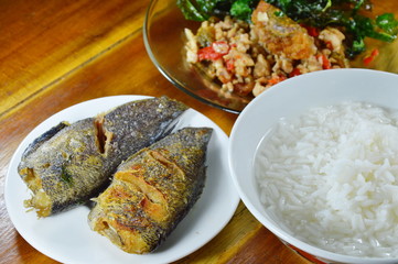 rice porridge eat with stir fried crispy basil leaf with black preserved egg and deep fried fish