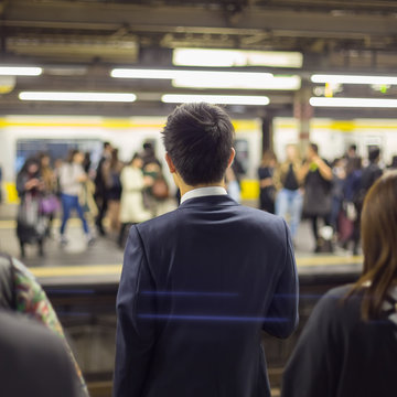 Passengers traveling by Tokyo metro. Business people commuting to work by public transport in rush hour. Shallow depth of field photo. 