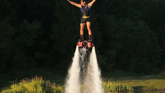 Man on the flying board on the river, water jet spray.Man on the flying board flies over the lake water.Fly board rider.new water sport called fly board.