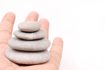 Fototapeta na wymiar Hand holding balanced grey stones over white background