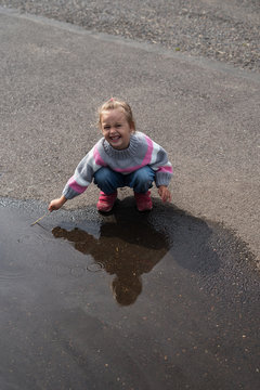 Little girl playing in a big puddle