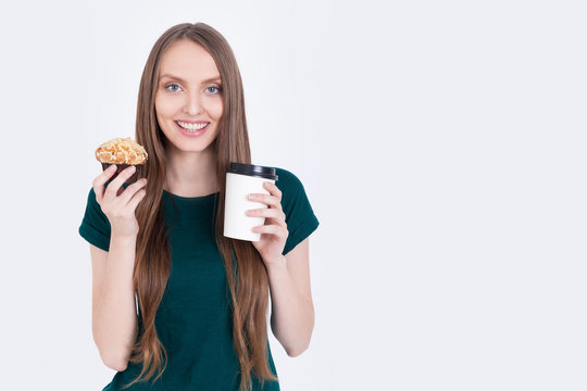 Girl in green T-shirt holding cupcake and coffee
