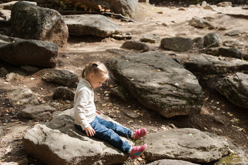 Little girl sitting on a big stone