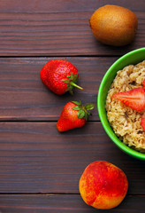 oatmeals in green plate decorated with slice of strawberry. Kiwi