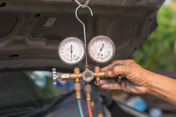 Dirty hands holding a manometers on equipment for filling air conditioners