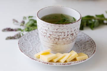 cup mint tea in old mug on saucer with cheese