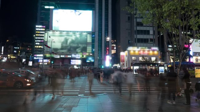 Timelapse shot of crowd of unidentified pedestrians crossing the road at traffic lights in big night city of Seoul, South Korea