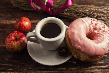 fresh donut with coffee on wooden table with napkin, spoon and c