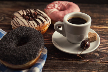 fresh donut with coffee on wooden table with napkin, spoon and c