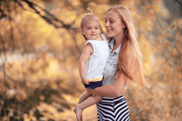 Mom holding daughter in her arms autumn photos in yellow park
