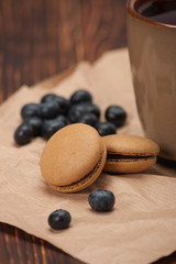 Fototapeta na wymiar Macaroon Biscuits, Blueberries On Paper. Wooden Table