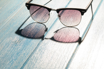stylish sunglasses on blue wooden table with sunlight