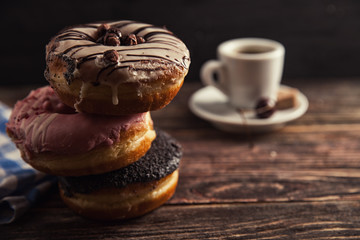 fresh donut with coffee on wooden table with napkin, spoon and cherry