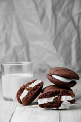Broken cookies and stack of sponge cookies with cream on paper. closup.glass with milk defosused on second plan.Selective focus.vertical shot