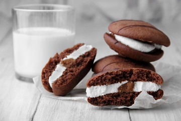 Broken cookies and stack of sponge cookies with cream on paper. closup.glass with milk defosused on second plan.Selective focus