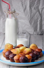 chocolate and simple mini muffins with on white blue plate.Selective focus.Closeup.Bottle and glass of milk on second plan defocused.