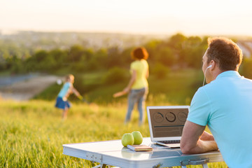 Handsome man enjoying laptop outdoors
