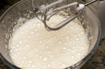 Frothy white liquid in glass mixing bowl
