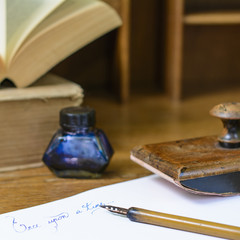 Text “Once upon a time” written in ink on paper sheet surrounded with a fountain pen, an ink...