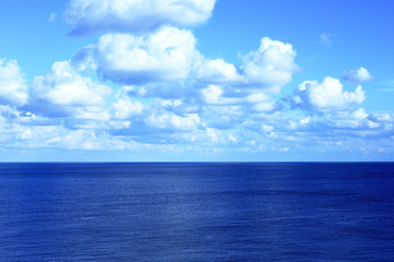 Blue sea with fluffy clouds and blue sky.