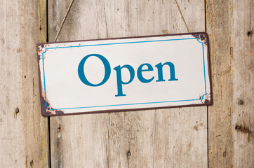 Old metal sign in front of a rustic wooden wall - Open