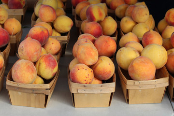 Wood baskets of peaches at an outdoor farmers market