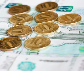 10 rubles coins against background of 1000 rubles banknotes