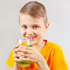 Little funny boy with a glass of green lemonade
