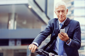 Fototapeta na wymiar Successful businessman on bicycle with mobile phone