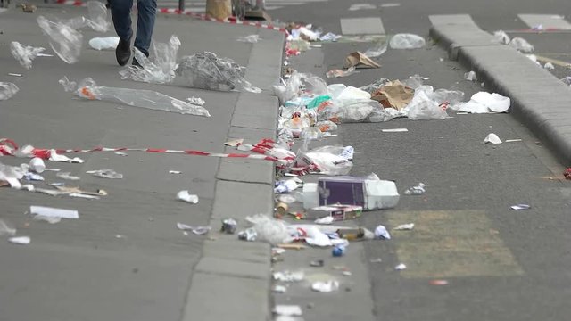 Legs walking on the street. Garbage on city road. Too much trash. Problem of modern society.