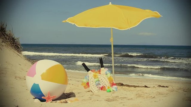 rackets and beach ball under a yellow parasol