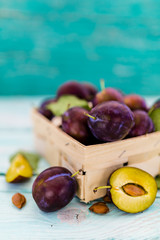 Ripe plums in a basket on a wooden table. Space for text.

