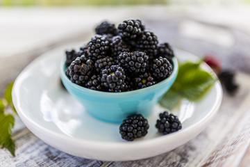 Fresh blackberries in bowl on wooden table in the garden