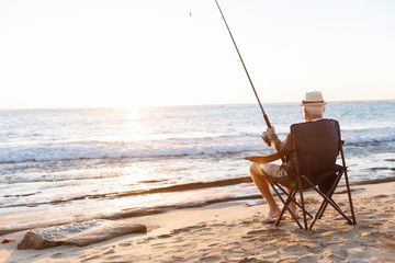 Senior man fishing at sea side - Powered by Adobe