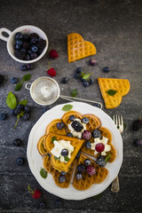 Homemade Belgian waffles with fresh ripe berries served on white plate.
