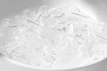 Pile ice in a white ceramic bowl, close up cold water in a circle plate