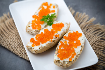 Red caviar on bread on white plate.
