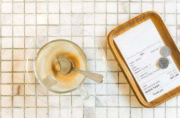Bill receipt and empty coffee latte cup on white marble table