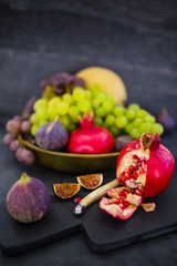 Beautiful still life with grapes and figs, pomegranate and other fruits on stone background.
