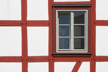 Fachwerkhausfassade mit Fenster / Die Nahaufnahme der Balkenkonstruktion eines Fachwerkhauses mit Fenster.