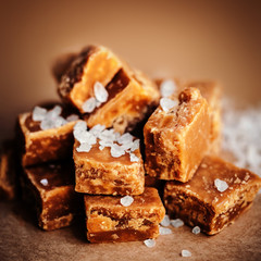 Salted caramel pieces and sea salt close up, top view. Buttersco