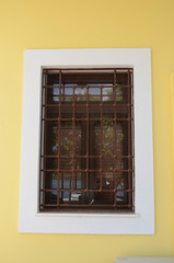 Metal grid over window on yellow wall,Argostoli, Kefalonia,Greece, 