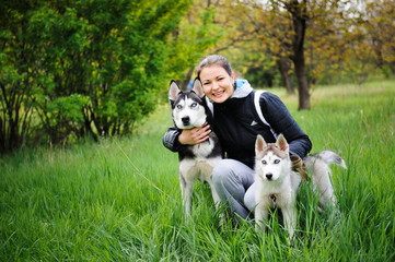 A girl and her dogs husky walking in a park