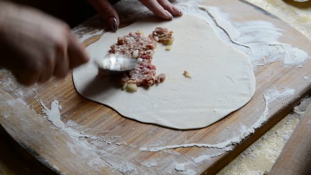 Housewife making chebureks from dough and sausage meat