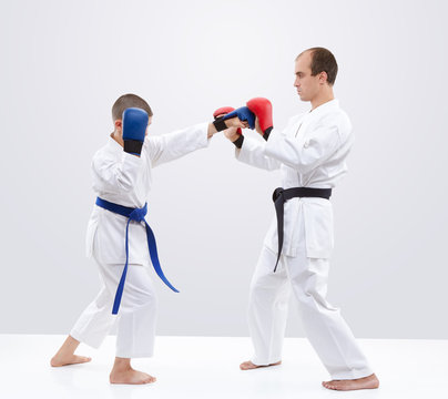 Boy karateka is  training strikes on the trainer overlays