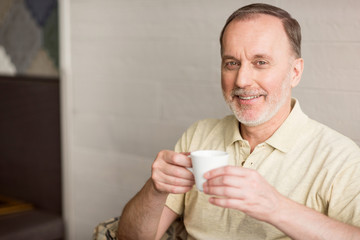 Cheerful senior man drinking coffee