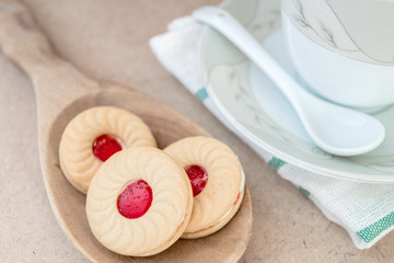 Sweet cookies with cream and jam on wood background