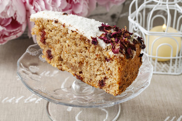 Carrot vegan cake with coconut icing and dried wild rose petals