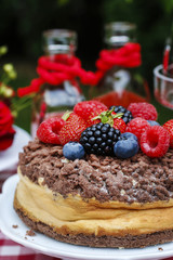 Cheesecake with chocolate topping decorated with summer fruits