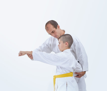 On a white background coach teaches the athlete to beat a punch arm
